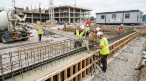 Béton bas carbone coulé sur un chantier technique avec coffrage, armatures et équipe de mise en œuvre, rendu éditorial réaliste.